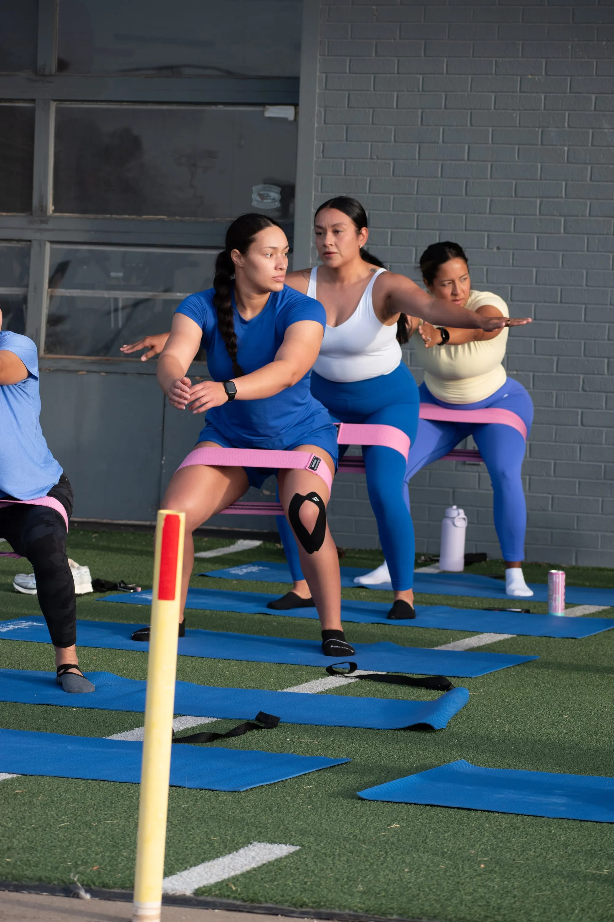 Members holding a banded squat together during an 806 Pilates class