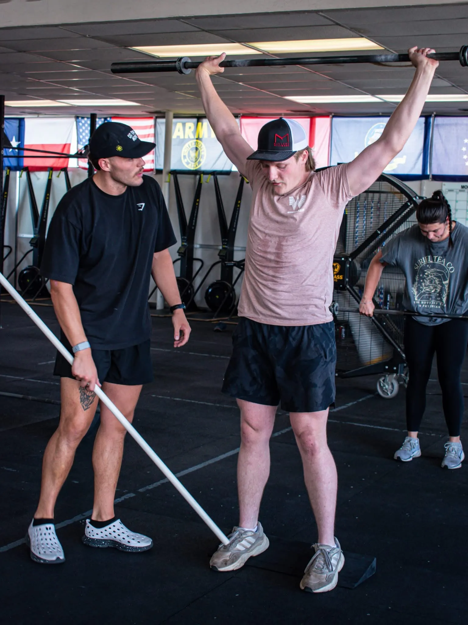 A coach cueing an athlete through an overhead barbell movement at CrossFit 806