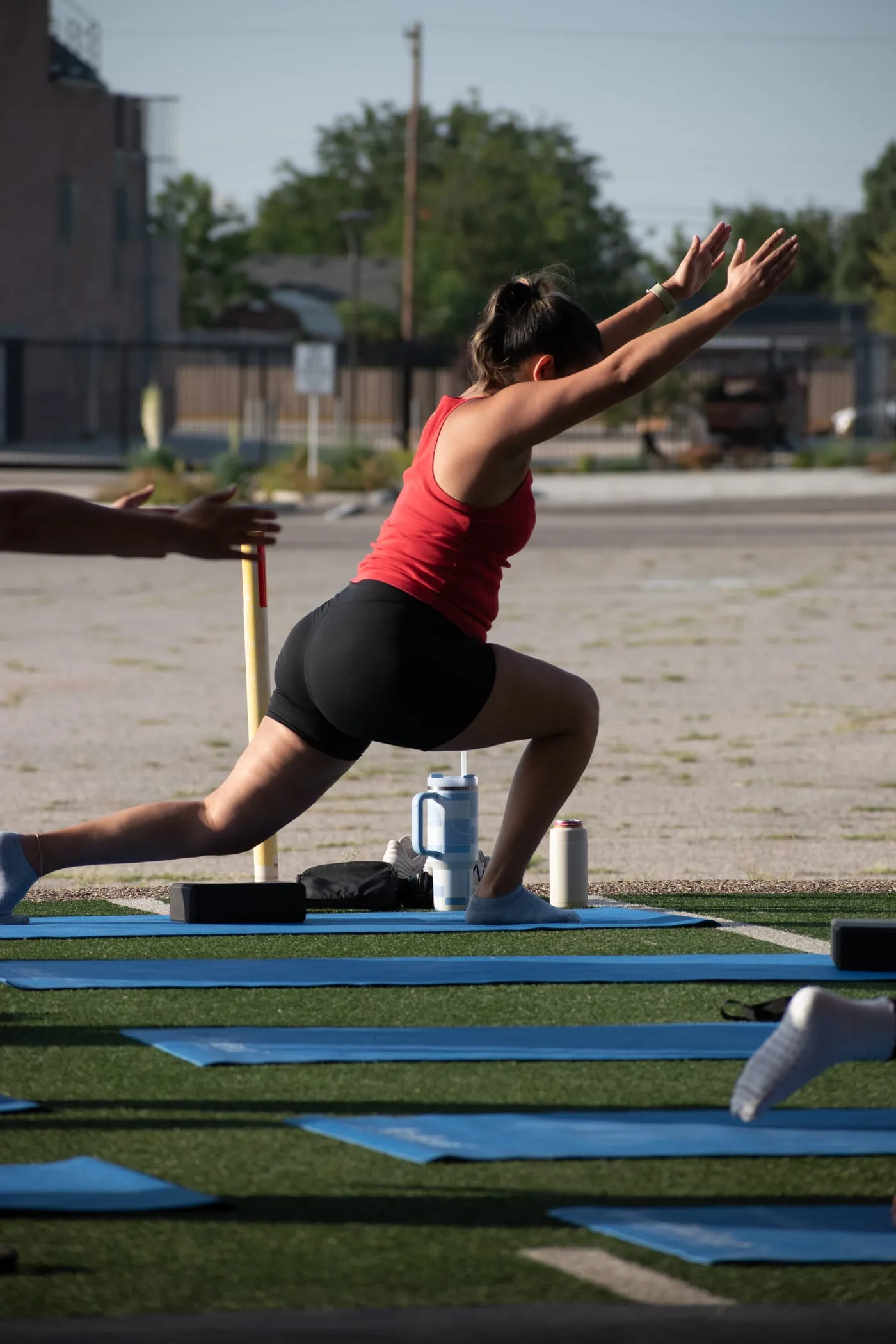 A member holding a controlled lunge with arms extended overhead during Pilates